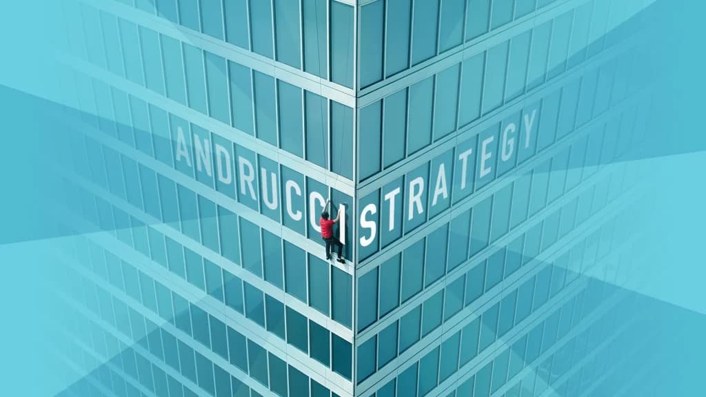 A man in a red shirt scales a tall skyscraper with the words “Andrucci Strategy” shown in the windows on a light blue background.