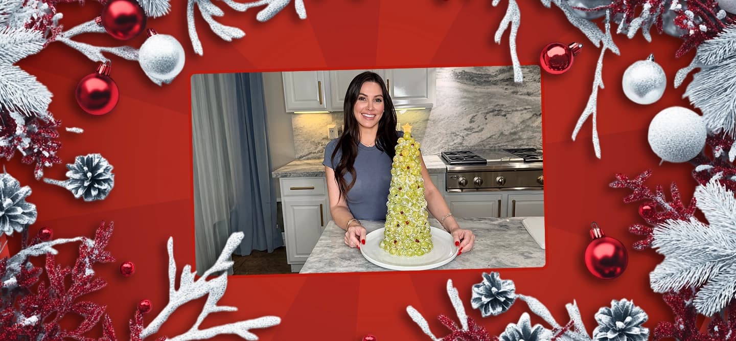 Chef genevieve presents her prosecco grape christmas tree surrounded by baubles and frosted pine branches on a red background