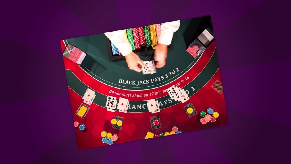 Overhead view of a blackjack table showing cards, chips, and a dealer’s hands during a game.