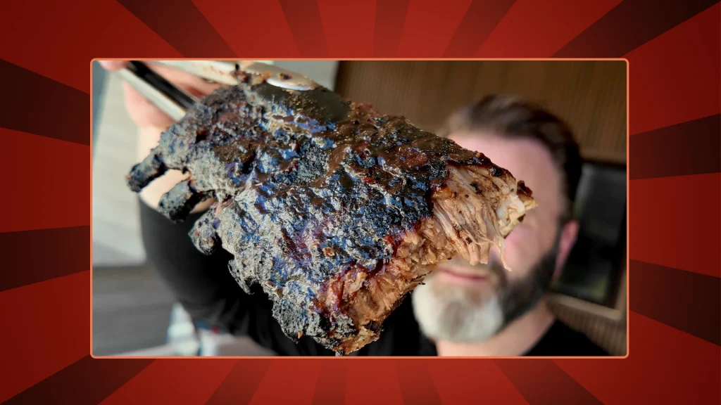 Chef Eric James holds up his oven roasted baby back ribs on a red background
