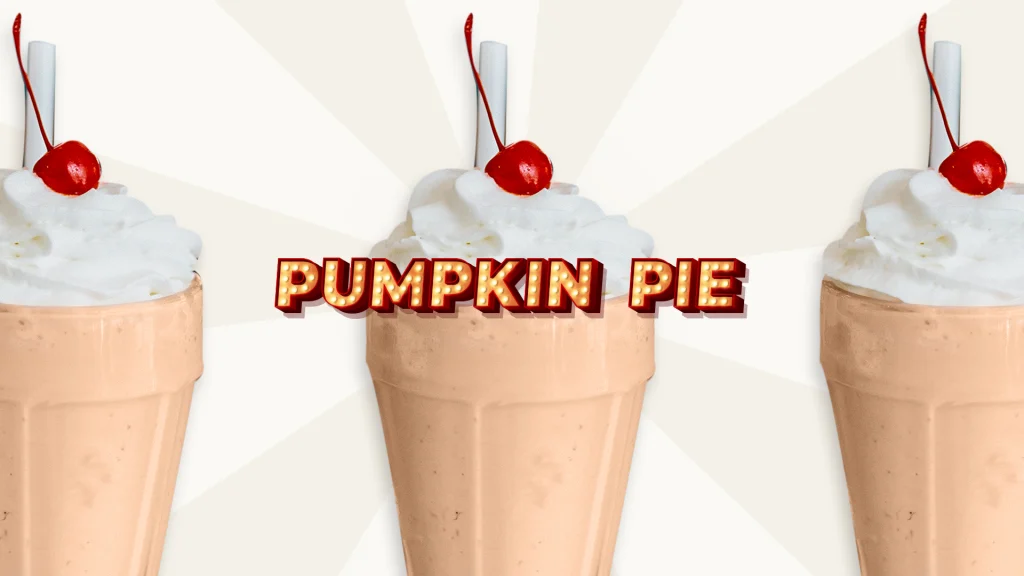 A tall pumpkin pie milkshake with cream and a cherry on top in the background, with the words “Pumpkin Pie” in a Vegas-style sign in front.