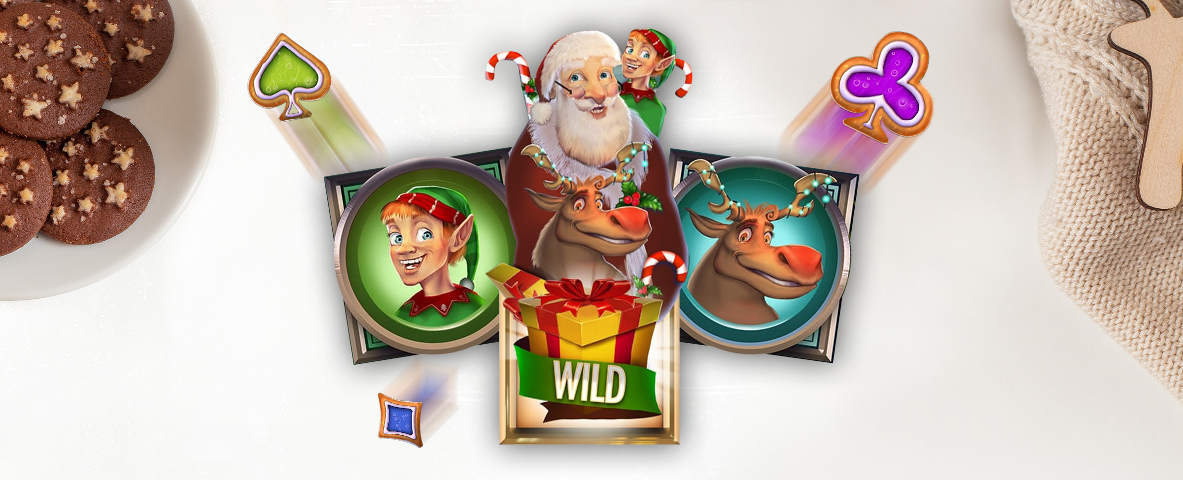 3D animations from the Cafe Casino slot game Santa’s Ways Hot Drop Jackpots are seen in the middle of the image, featuring an elf, a reindeer, and a yellow gift box wrapped in a green ribbon with the word “wild”, with a reindeer, Santa Claus and an elf blooming out from the center. Either side, there are chocolate cookies on a plate, and a beige knitted sweater.