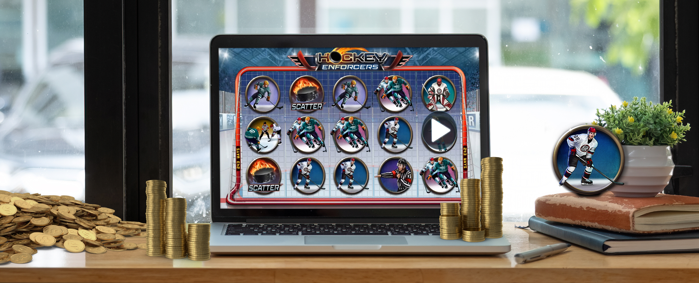 A MacBook sits atop a cafe bench, open, previewing a Cafe Casino slot game “Hockey Enforcers”, flanked either side by stacks of gold coins. To the right, two books prop up a pot plant and a picture frame of a hockey player, and to the left, sits a large pile of coins