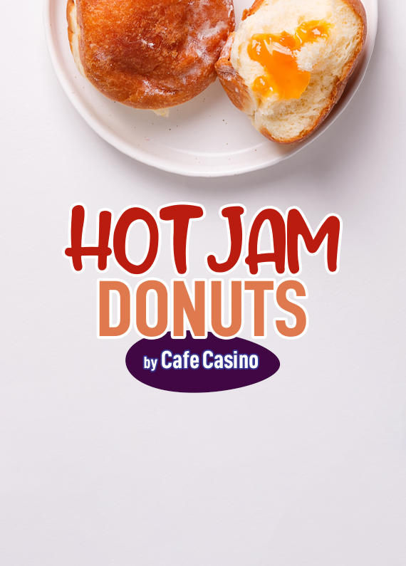 A white plate sits on top of a white counter bench, and on it, are two donuts - one of which is cut in half with cream and apricot jam placed on it. Below it are words that read “Hot Jam Donuts by Cafe Casino”.