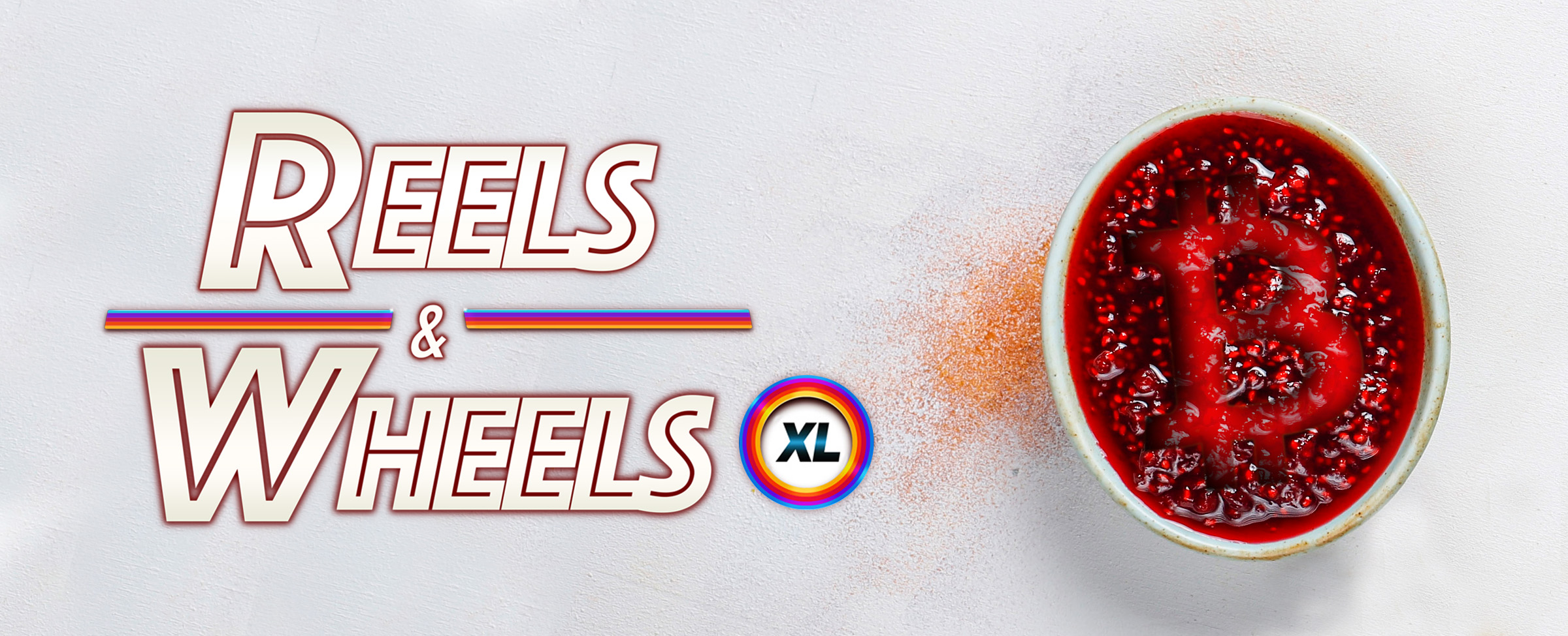 The logo from the Cafe Casino slot game, Reels and Wheels XL, is pictured on the left of the image, hovering above an off-white table surface. To its right sits a coffee mug filled with a red liquid, stamped with a large letter B in the style of Bitcoin.