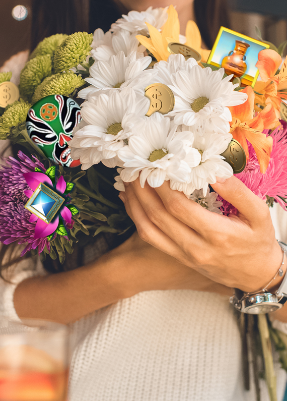 A woman holds a colorful bouquet of flowers in front of her, while three symbols from Cafe Casino slots games sit amongst it.