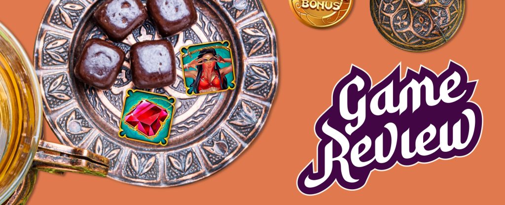 Four Arabian sweets sit inside a brass plate, alongside two symbols from the Cafe Casino slot game, Oasis Dreams Hot Drop Jackpots. Off to the right is a small brass trinket and a gold coin that reads ‘bonus’. Below, read the words, “game review”.