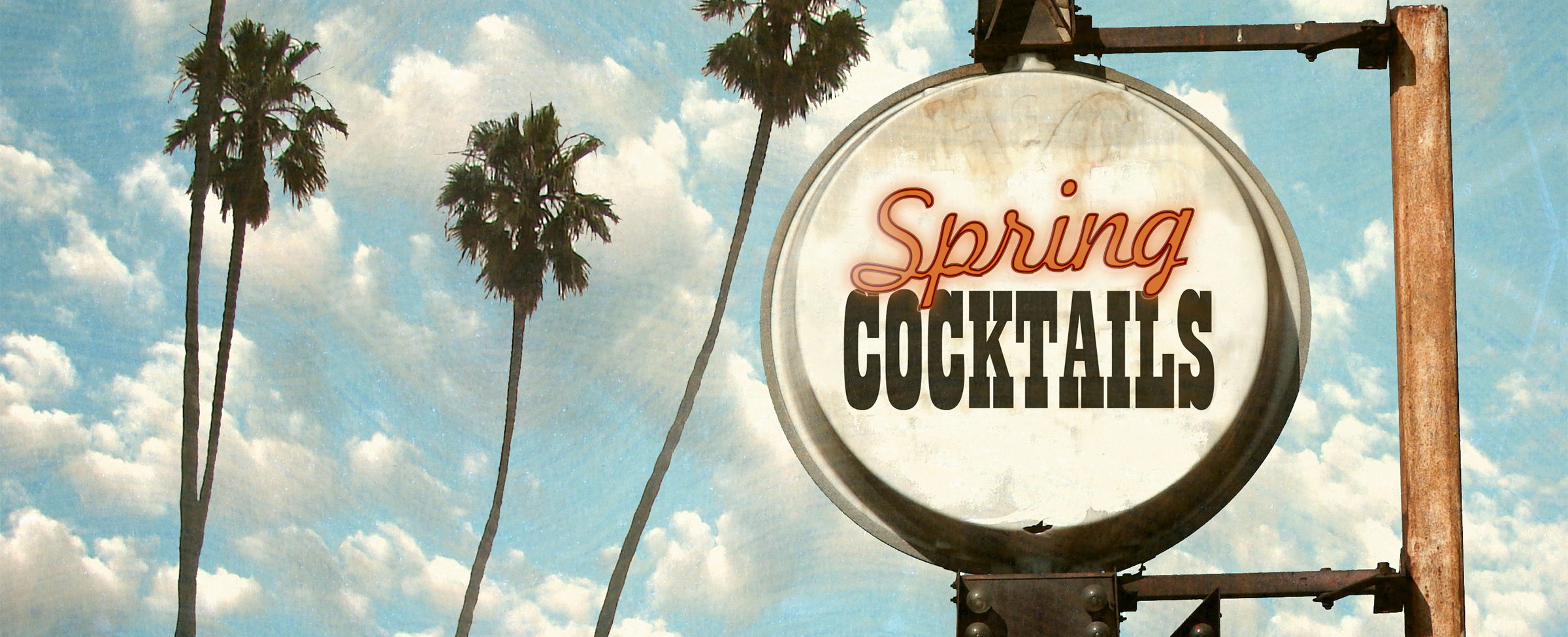 An industrial, vintage-style backlit sign hangs on a steel post featuring the words “spring cocktails” in red and black against a white background. Behind, is a blue sky peppered with light clouds, and four tall and skinny palm trees swaying in the breeze.