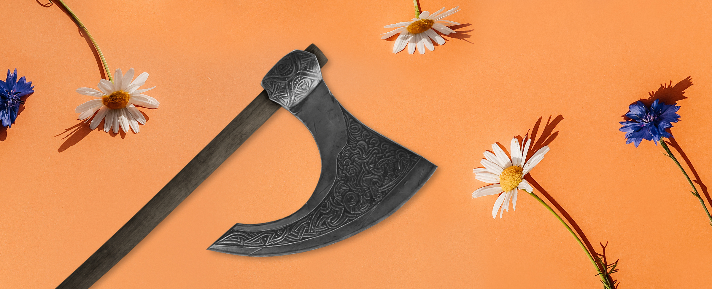 A Viking ax with a patterned blade and a worn wooden handle rests on an apricot-colored table surface, surrounded by blue and white flowers.