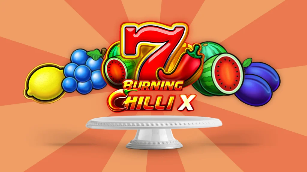 Slot game graphics from ‘Burning Chilli X’ appear above a cake stand, flanked by various fruit icons and the number 7, set against an apricot background.