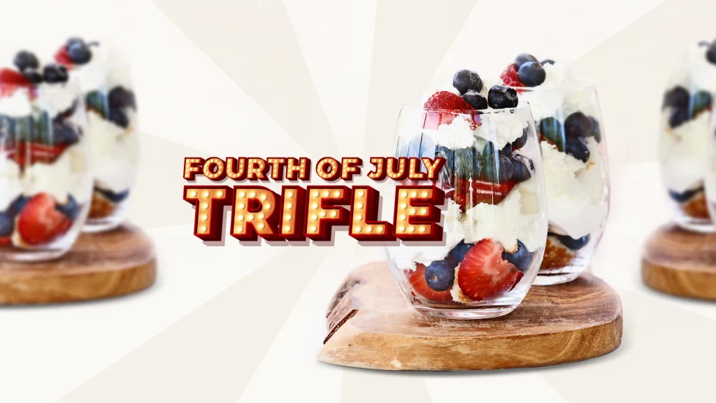 Drink glasses on top of a wooden platter filled with trifles, in the fourth of July colors, featuring strawberries and blueberries surrounded by freshly whipped cream.