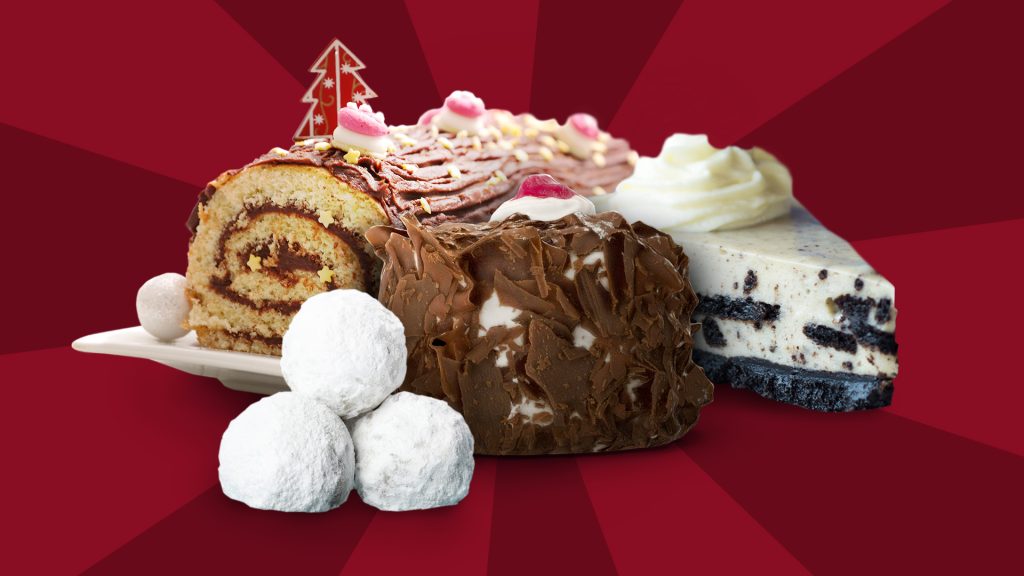 An assortment of Christmas desserts including snowball cookies, Black Forest cake and yule log, on a red background.