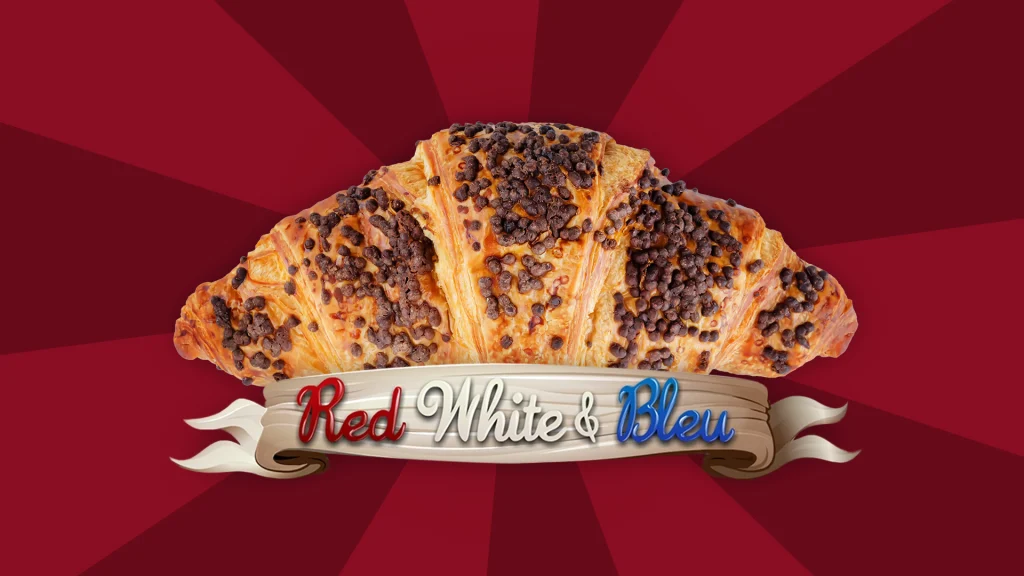 The logo of the Cafe Casino online slot Red White & Bleu superimposed over a French style croissant on a vibrant red background.
