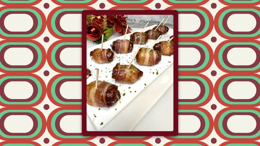 Bacon-wrapped dates sit on a white dish with toothpicks sticking out of the top; a festive floral arrangement is behind.