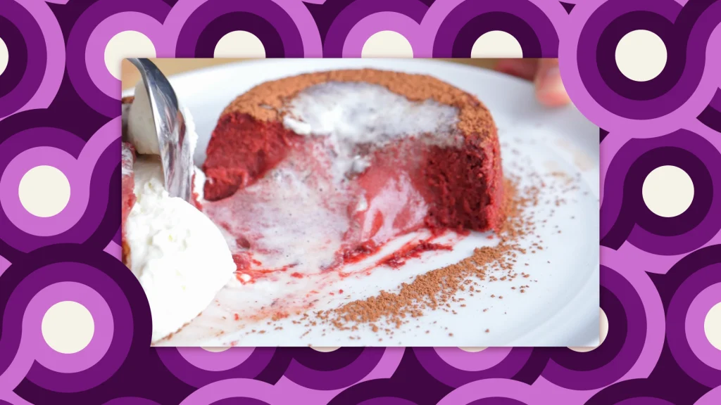 A round, red velvet lava cake, with a piece cut out of it, so the pink center is melting outwards.